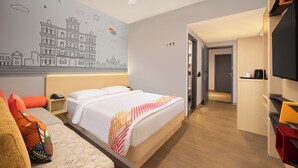 Habitación de hotel con cama, escritorio, televisor y un mural en la pared.