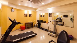 Un gimnasio con cintas de correr, mancuernas y un espejo.