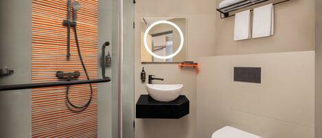 A modern bathroom with a glass-enclosed shower, a black sink, and a white toilet.