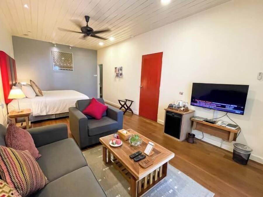A compact living space with a bed, a sofa, a coffee table, a TV, and a ceiling fan.