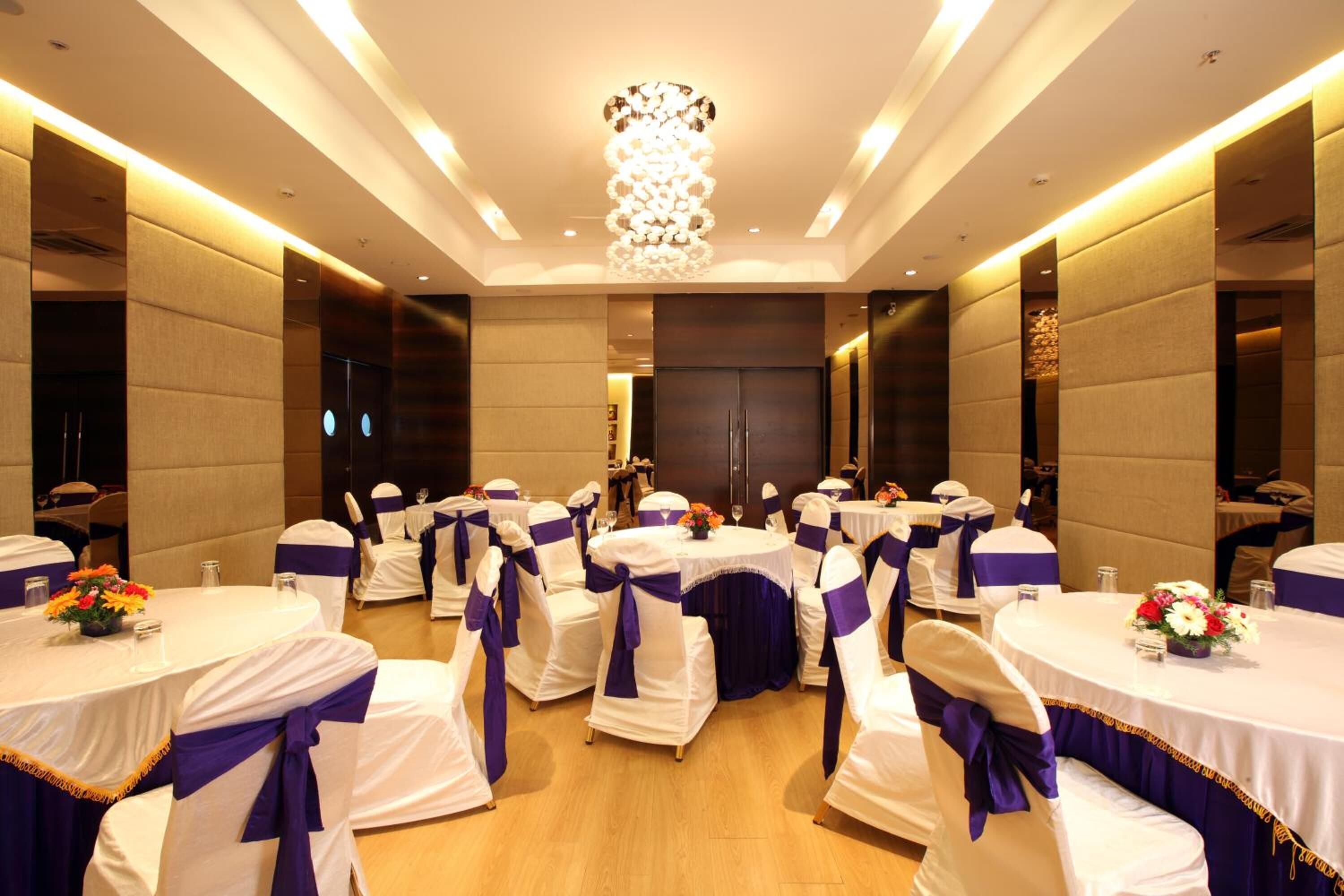 A banquet hall with round tables, white and purple tablecloths, and matching chair covers.