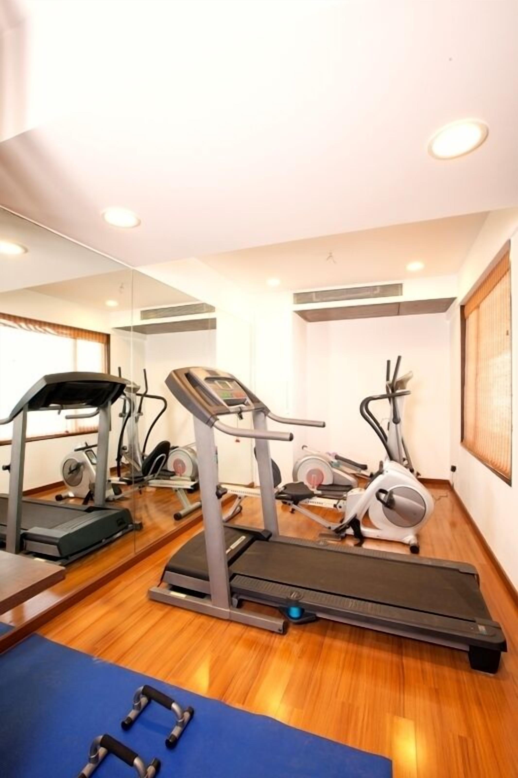 Un gimnasio con cintas de correr, elípticas y pesas libres.