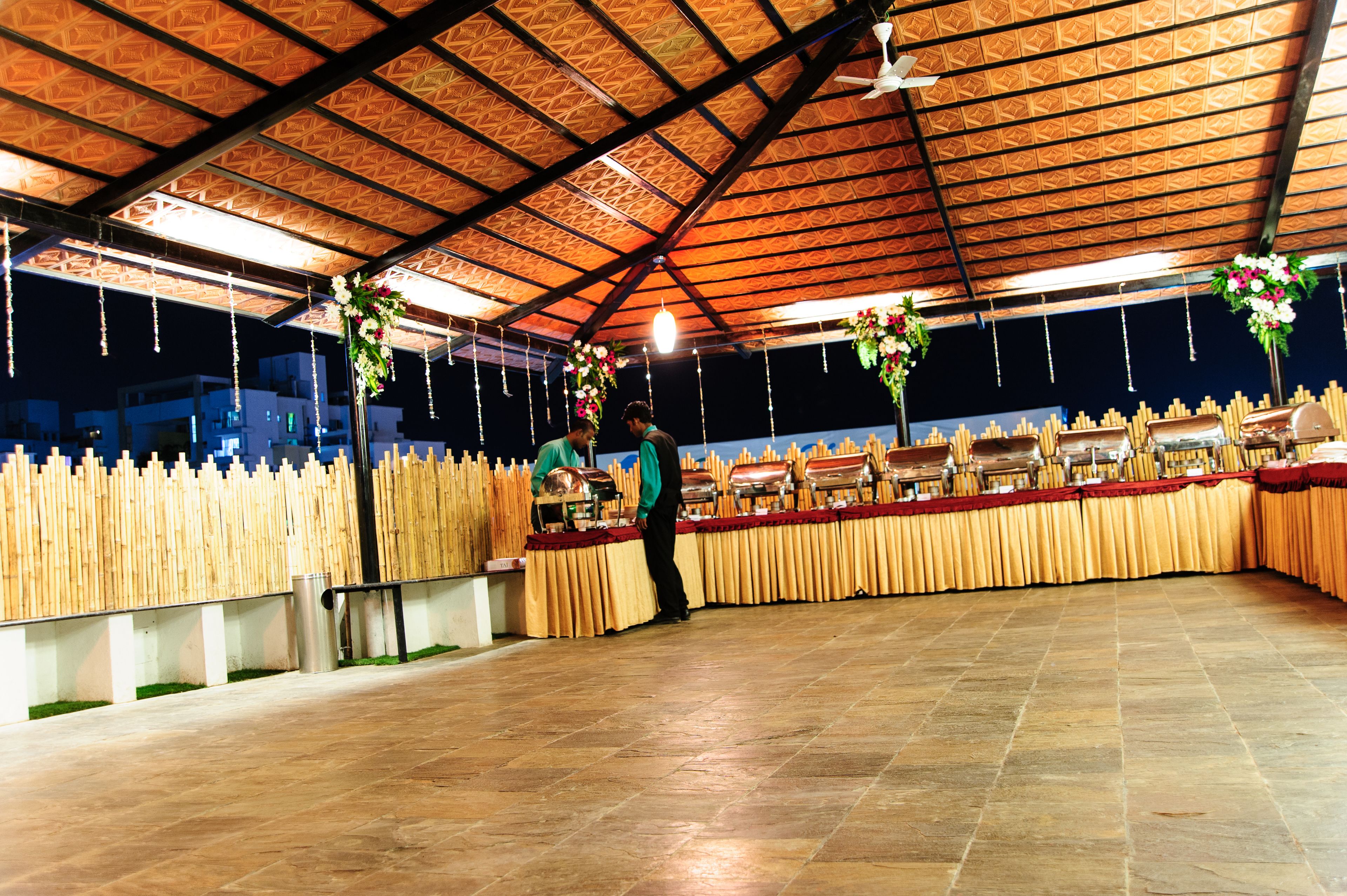 An indoor event space with a high ceiling, a buffet setup, and a wooden fence.