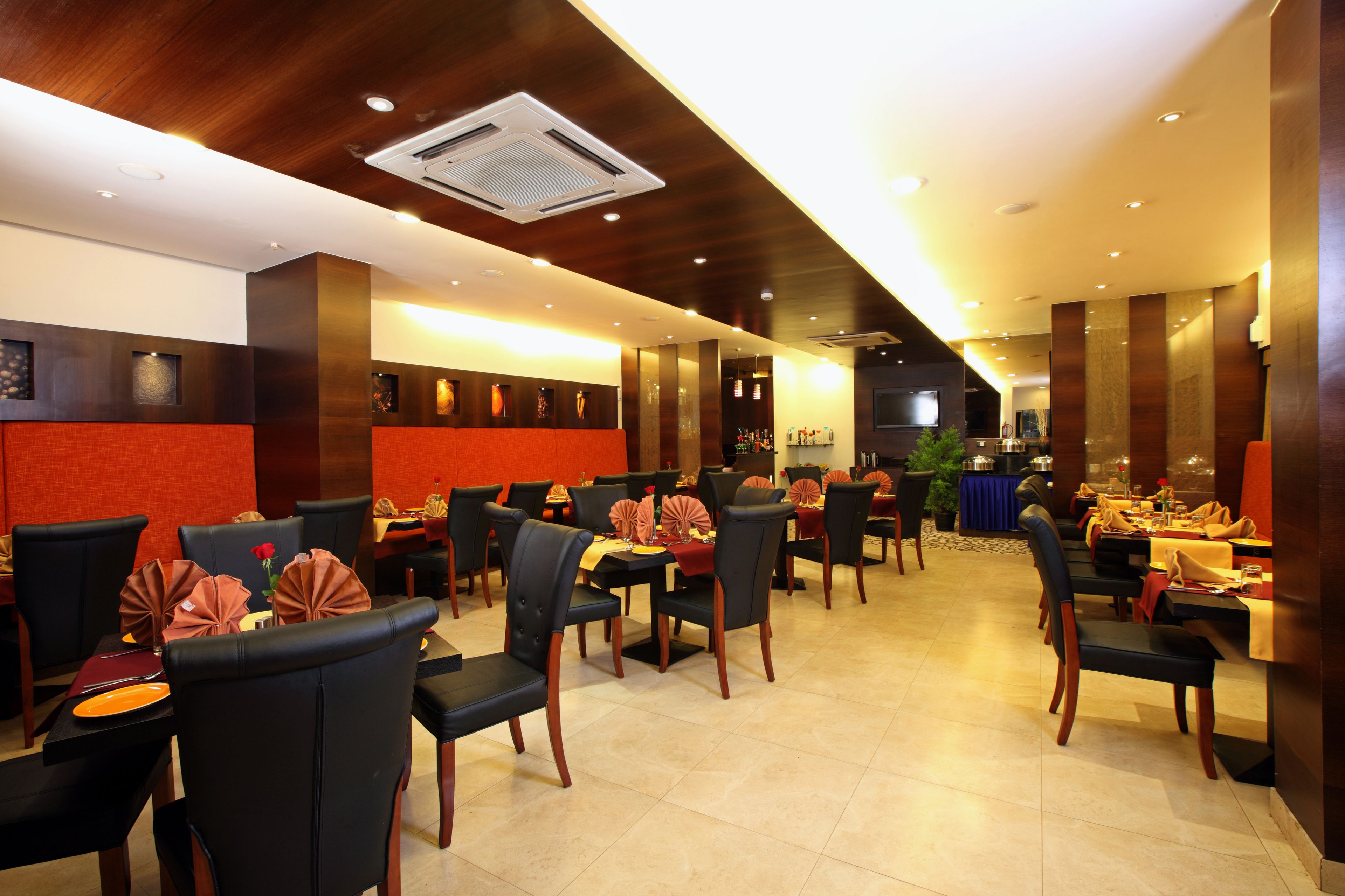 A restaurant with multiple tables and chairs, a ceiling with recessed lighting, and a wall-mounted air conditioning unit.