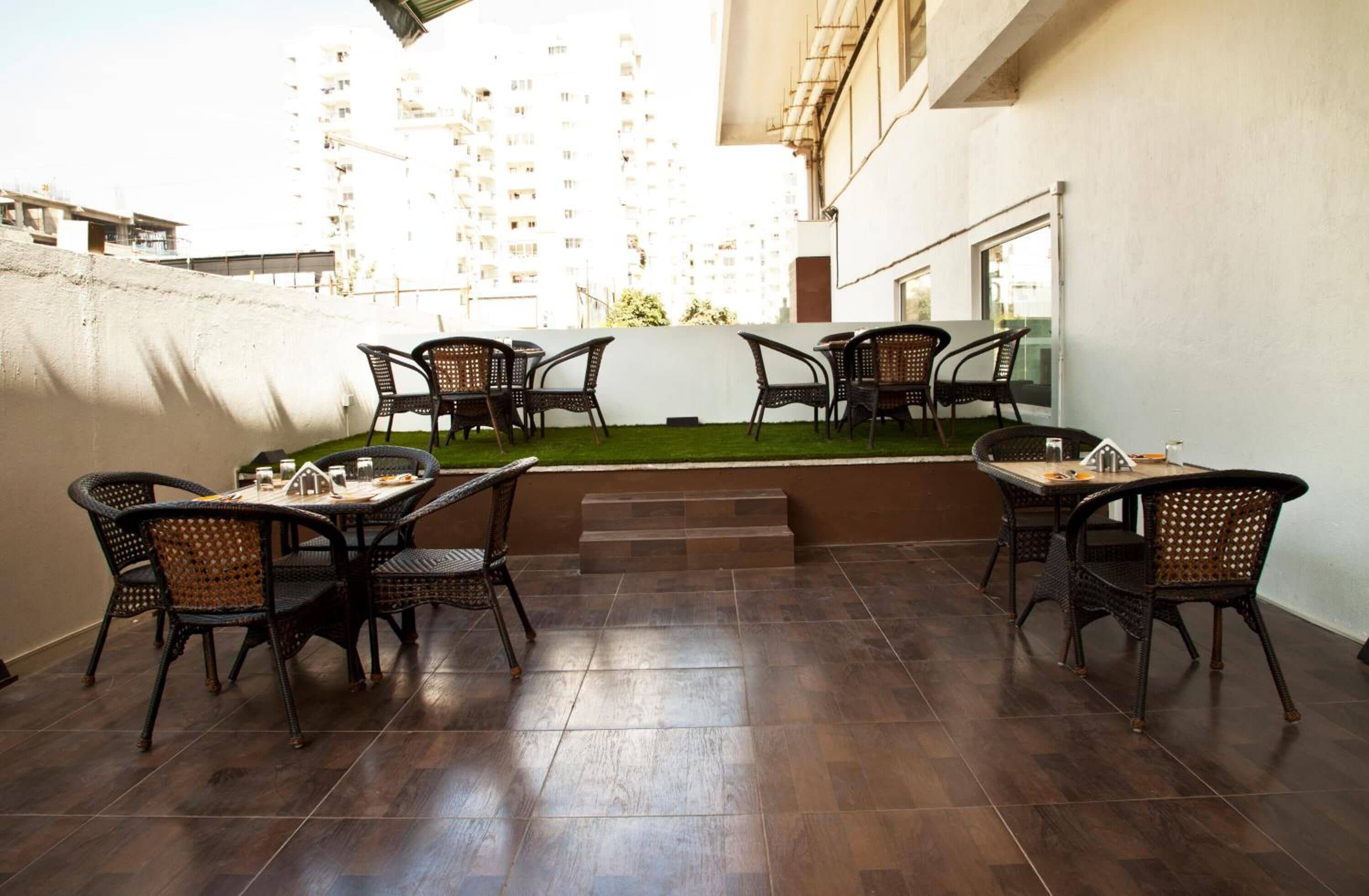 An outdoor patio area with dark tiled flooring, wicker chairs, and tables set up for dining.