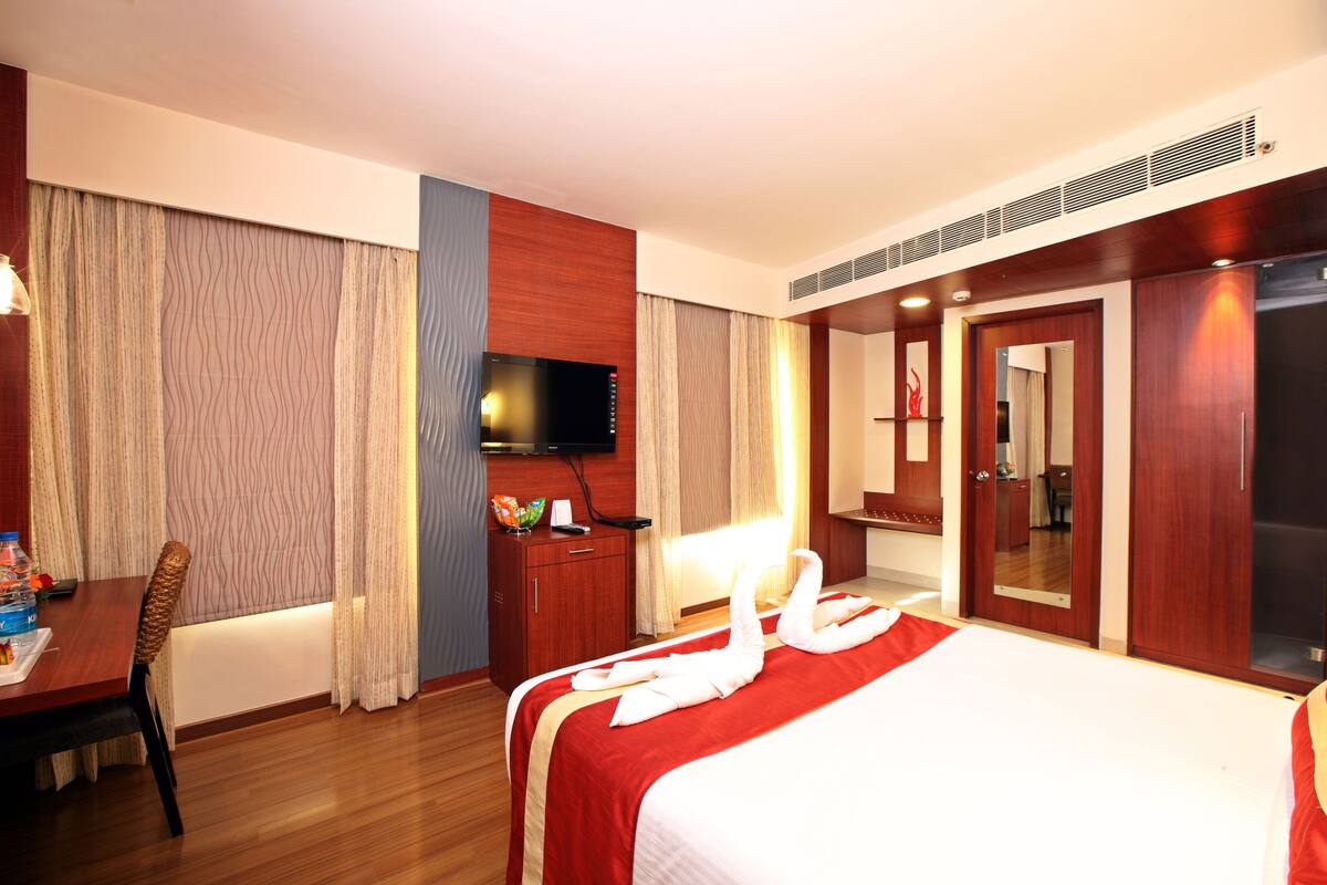 A hotel room with a bed, a desk, a television, and a wardrobe.