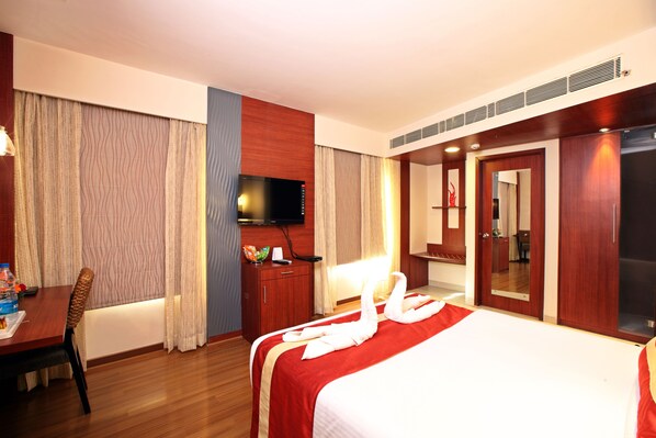 A hotel room with a bed, a desk, a television, and a wardrobe.