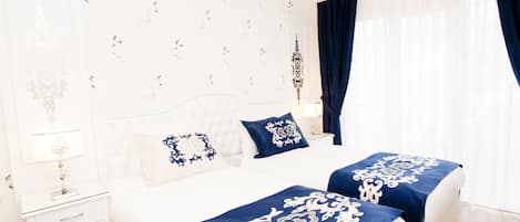 Quarto de hotel com cama, duas mesas de cabeceira e uma janela com cortinas.
