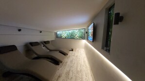A room with two reclining chairs, a large window with a view of greenery, and a flat-screen TV mounted on the wall. - Sarnic Premier Hotel - Special Class (Istanbul)