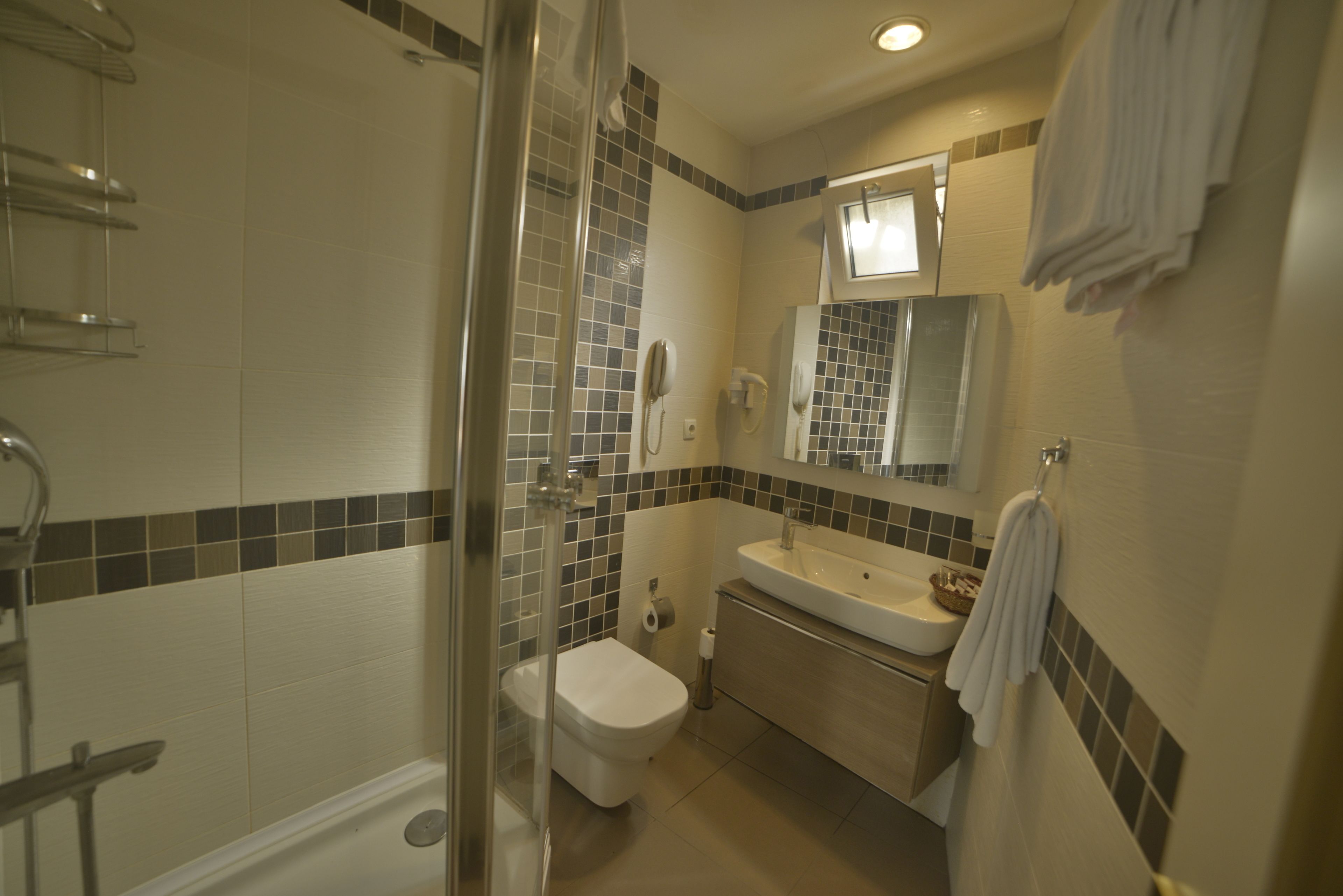 Une salle de bain avec une douche à parois de verre, des toilettes, un lavabo et un miroir au-dessus du lavabo.