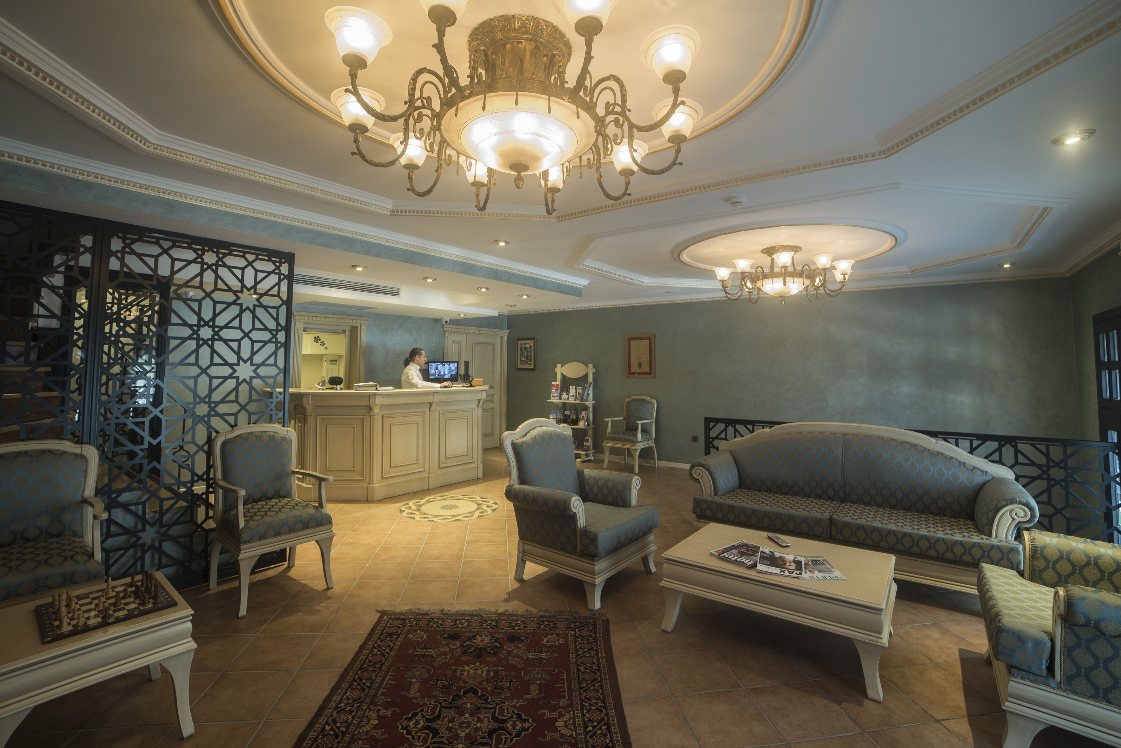 A spacious living room with a chandelier, sofas, armchairs, and a coffee table.