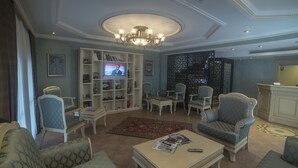 A spacious living room with a television, comfortable seating, and a bookshelf. - Sarnic Premier Hotel - Special Class (Istanbul)