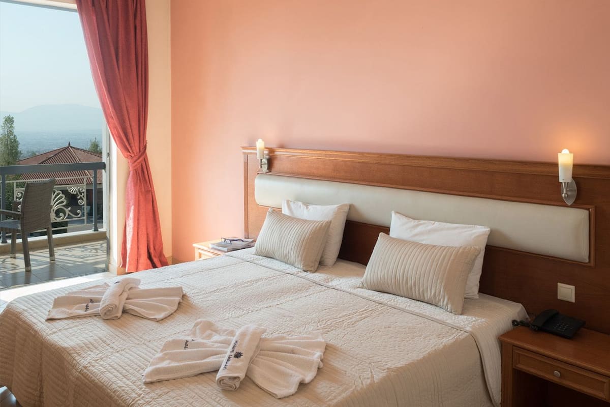 Ein Hotelzimmer mit einem großen Bett, zwei Nachttischen und Blick ins Freie.