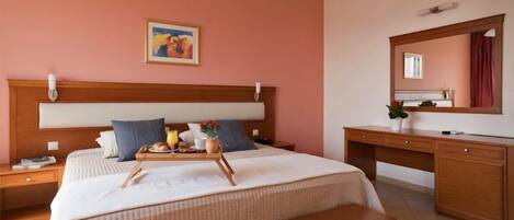 Un cuarto de hotel con una cama grande, un escritorio, un espejo y un cuadro en la pared.