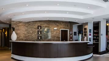 Un área de recepción con un mostrador curvo oscuro, una pared de piedra y un reloj.
