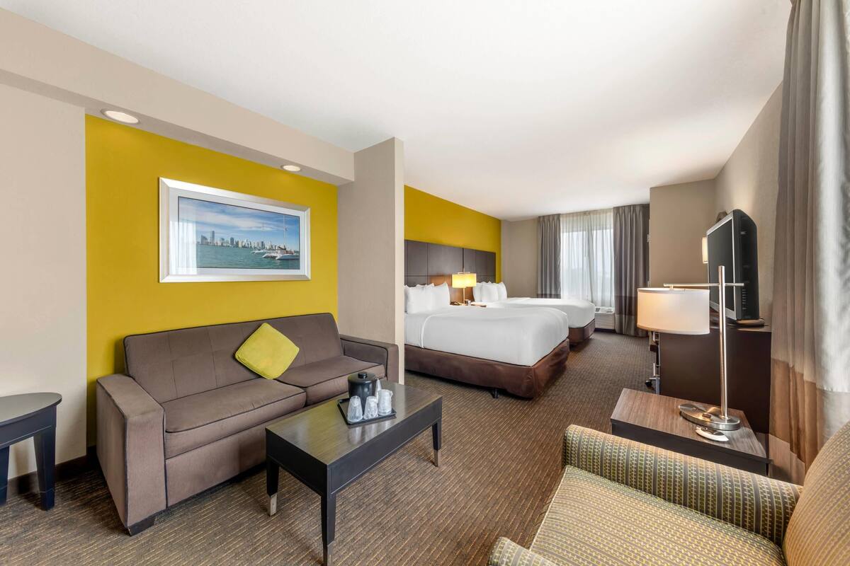 Una habitación de hotel con cama, sofá, mesa de centro y televisor.