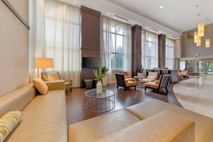 Un vestíbulo amplio con un sofá, sillones, una mesa de centro y una recepción.