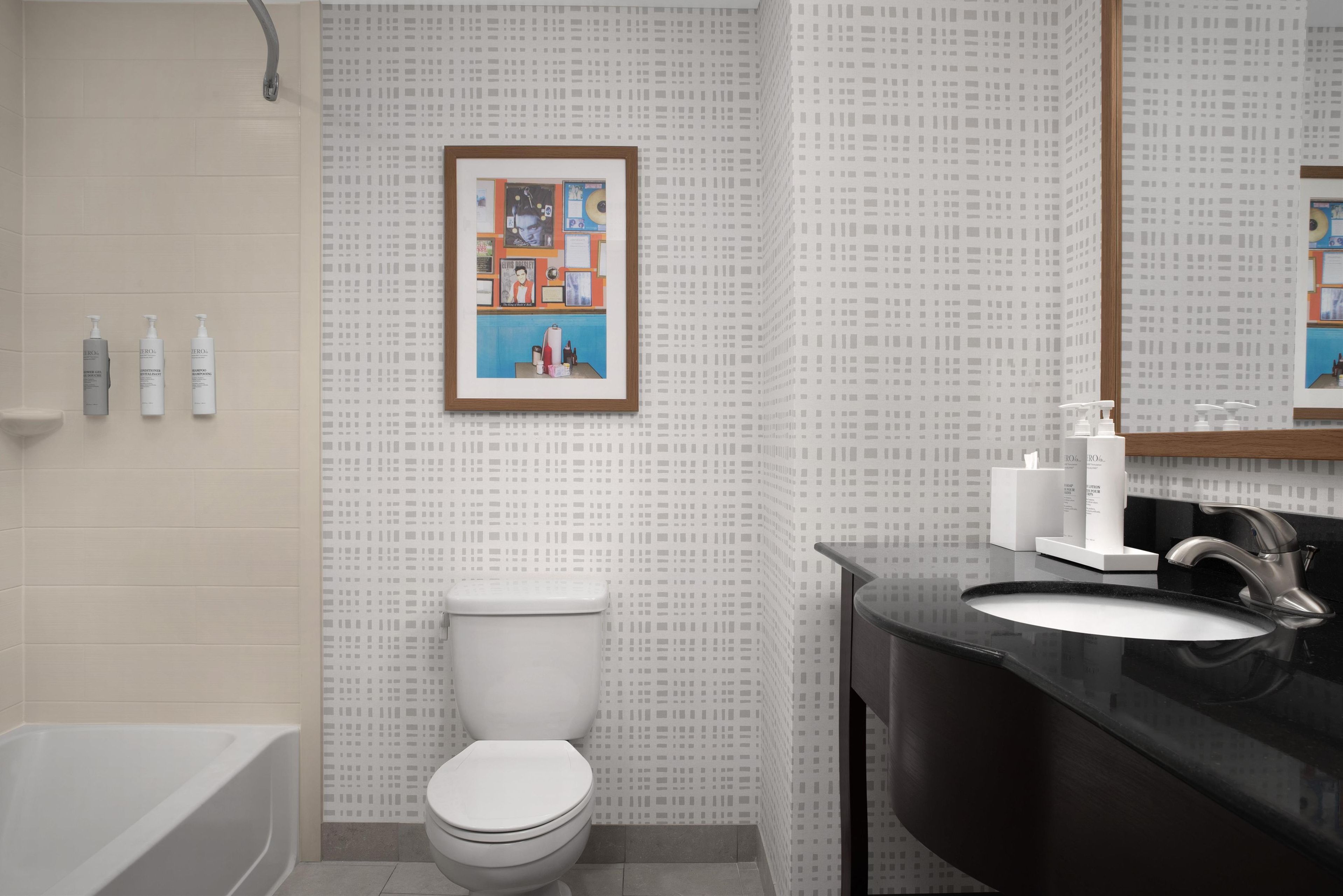 A modern bathroom with a white toilet, a bathtub, and a black sink.