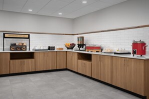A modern kitchen with wooden cabinets, a white tiled backsplash, and various appliances including a coffee machine and a red pot. - Hampton Inn & Suites Tupelo/Barnes Crossing (Tupelo)