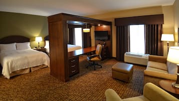 Una habitación de hotel con cama, escritorio, silla, reposapiés, televisor y calefacción.