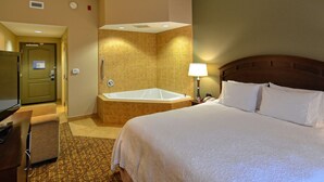 A hotel room with a bed, a desk, a TV, a bathroom with a bathtub, and a shower. - Hampton Inn Geneseo (Geneseo)