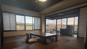 A room with tatami flooring, a low table, chairs, and large windows with a view of a mountainous landscape. - Ishicho (Kyoto)