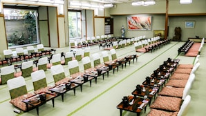 A conference room with rows of tables and chairs, large windows, and traditional decor. - Ishicho (Kyoto)