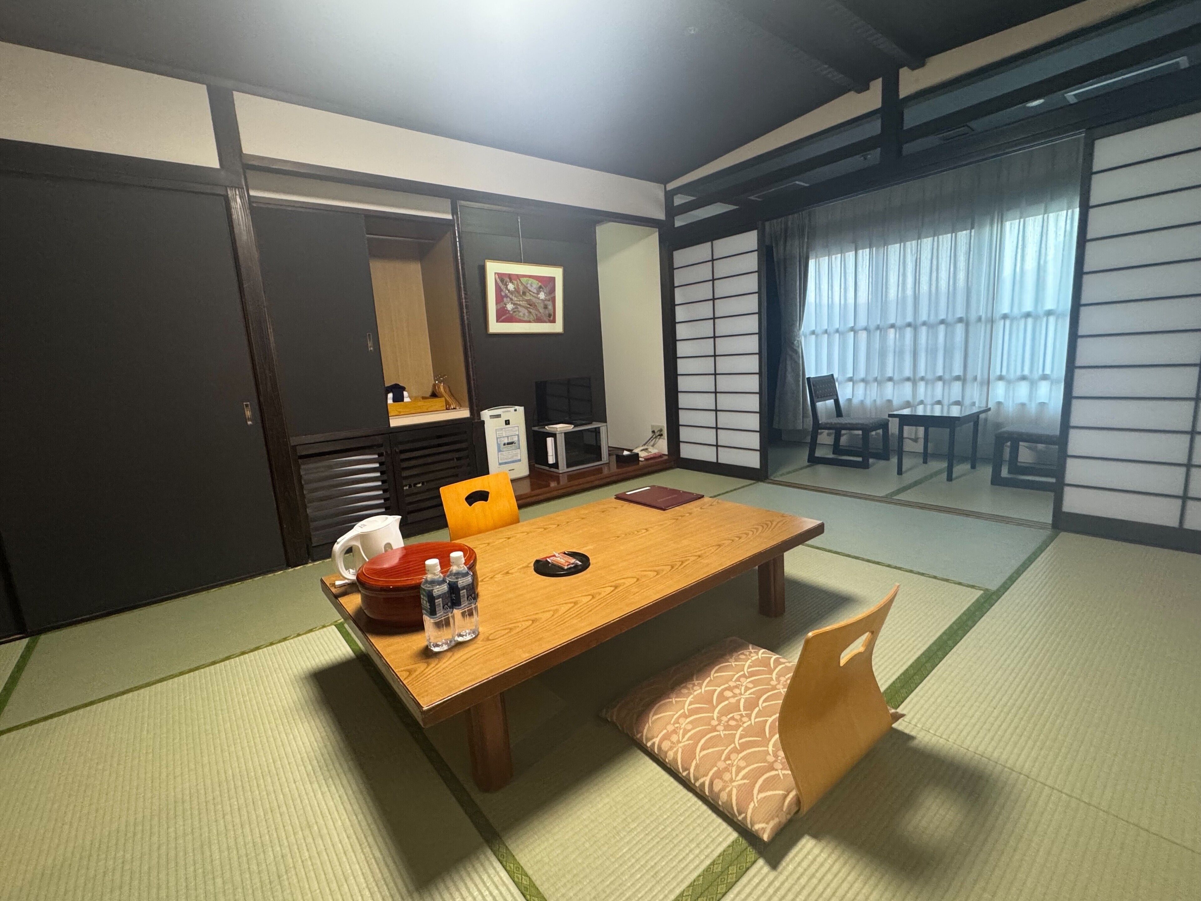 Egy hagyományos, japán stílusú szoba, tatami szőnyeggel, egy faasztallal és egy alacsony asztallal, melyre párnákat helyeztek.