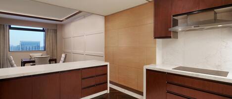 Una cocina moderna con armarios de madera, encimera blanca y un amplio ventanal con vistas a la ciudad.