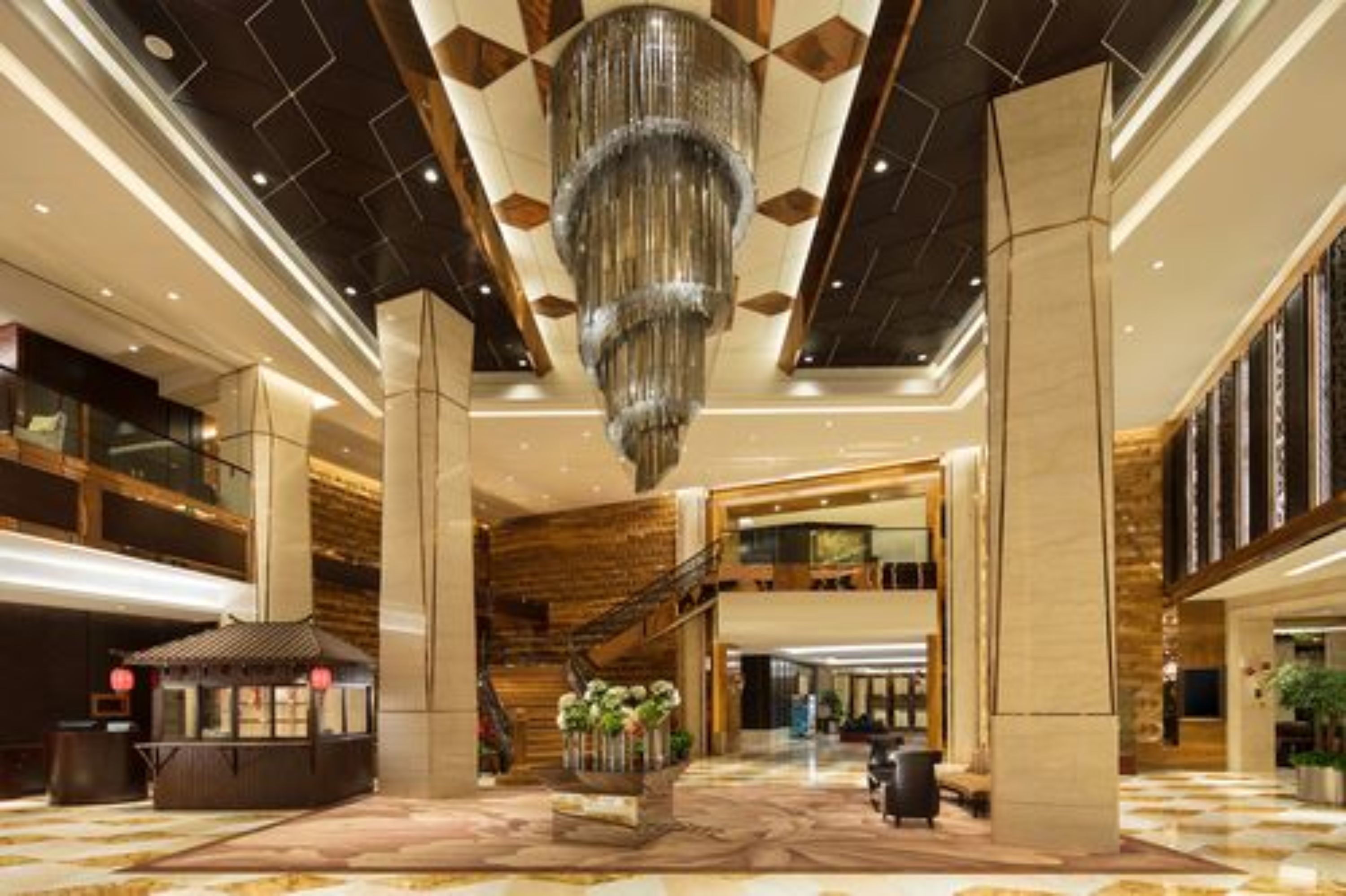 A spacious lobby with a grand chandelier, a traditional tea house, and a staircase leading to an upper level.