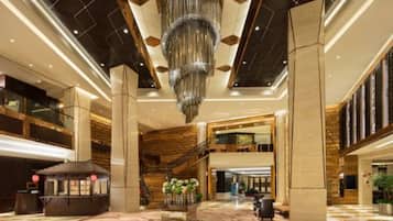 A spacious lobby with a grand chandelier, a traditional tea house, and a staircase leading to an upper level.