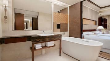 A modern bathroom with a freestanding bathtub, a large mirror, and a vanity with a marble countertop.