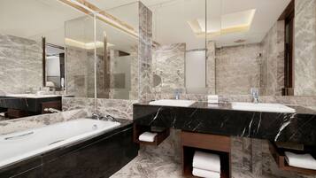 Un baño moderno con paredes de mármol, un espejo grande, una bañera y dos lavamanos.