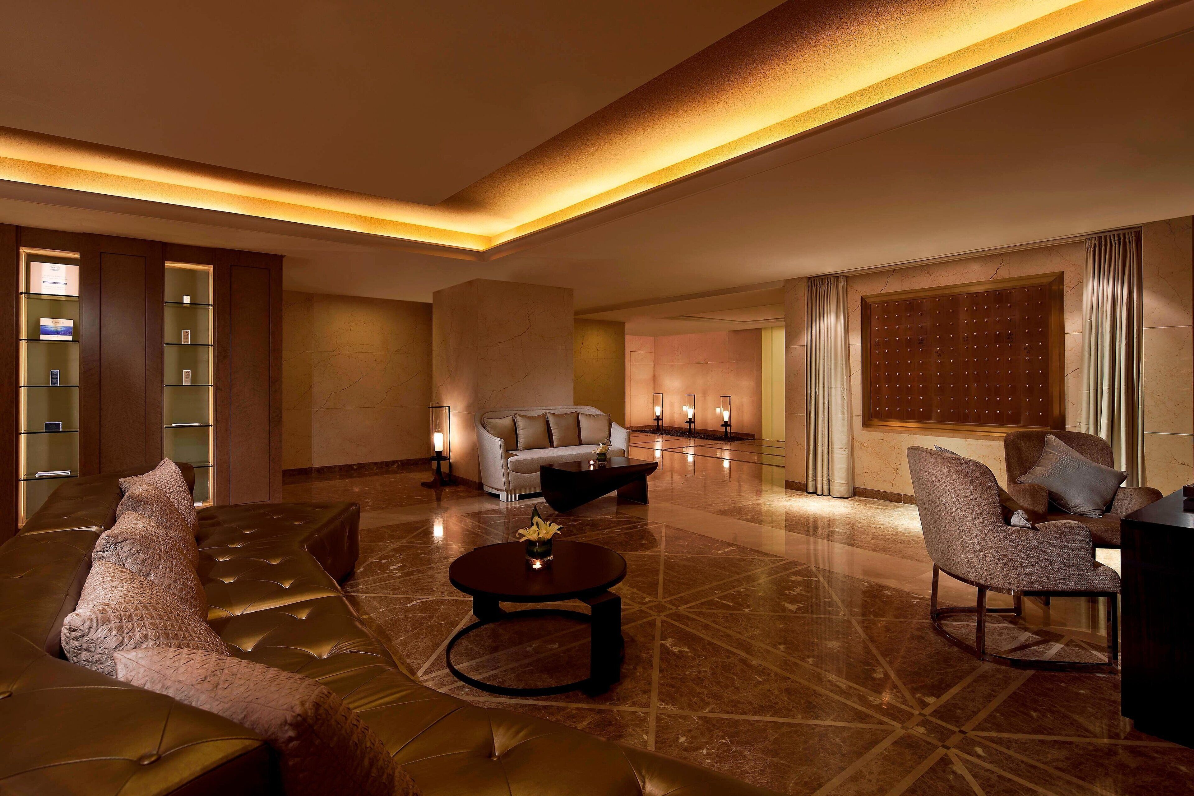 A spacious lobby with a leather sofa, armchairs, a coffee table, and a large window with curtains.