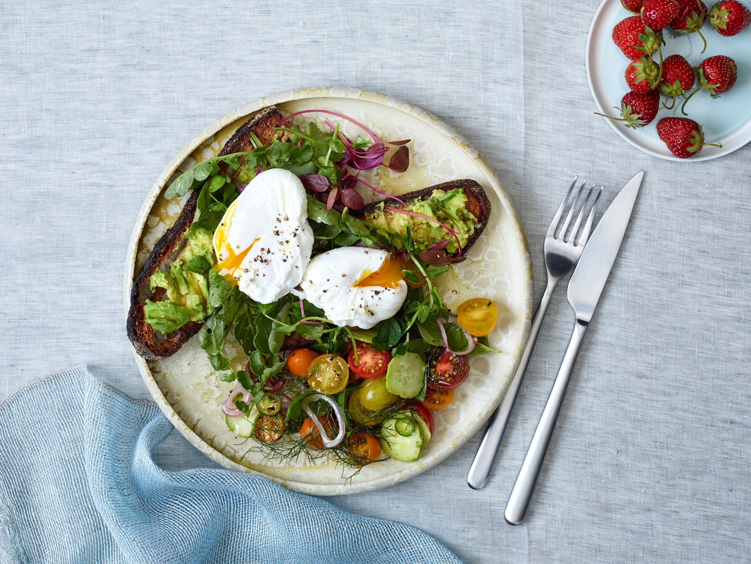 En tallerken mad med salat, æg og tomater.
