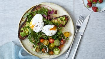 En tallerken mad med salat, æg og tomater.