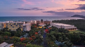 Un resort con varias construcciones, una edificación central con cúpula y vista al mar.