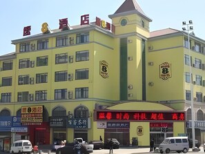 A multi-story building with a prominent yellow facade, multiple windows, and various signage.