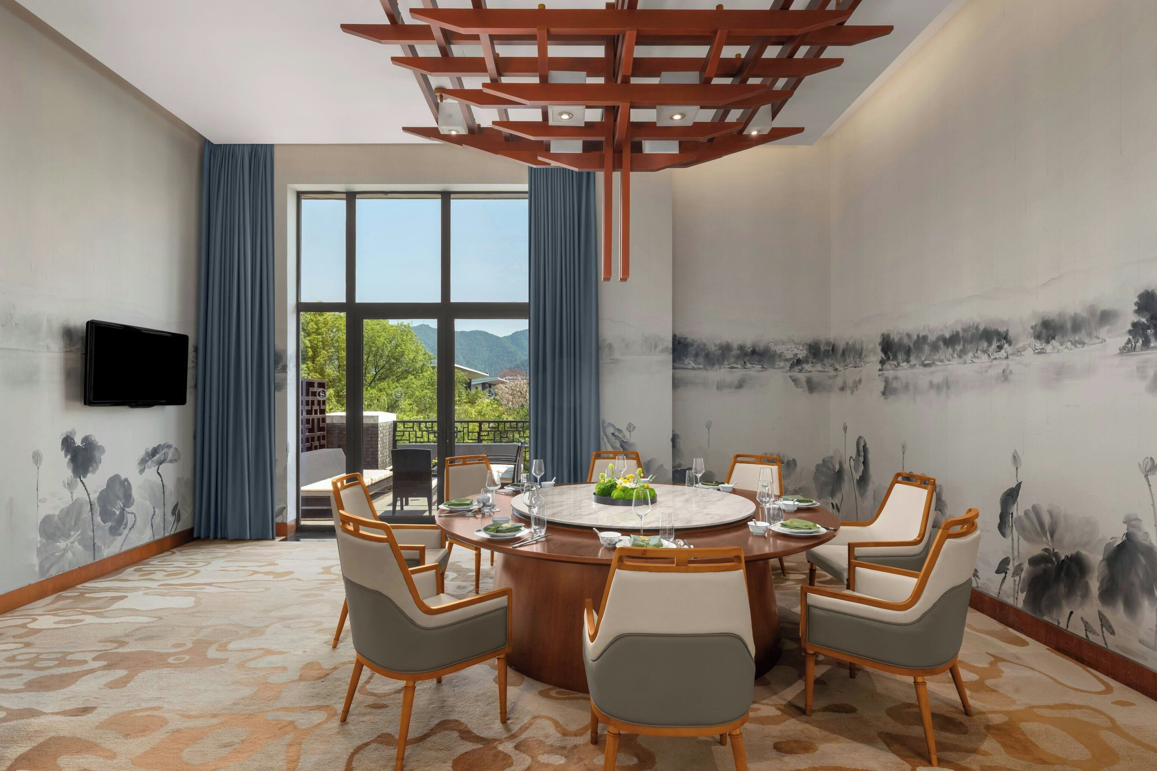 Une salle à manger moderne avec une table ronde, six chaises et un téléviseur fixé au mur.