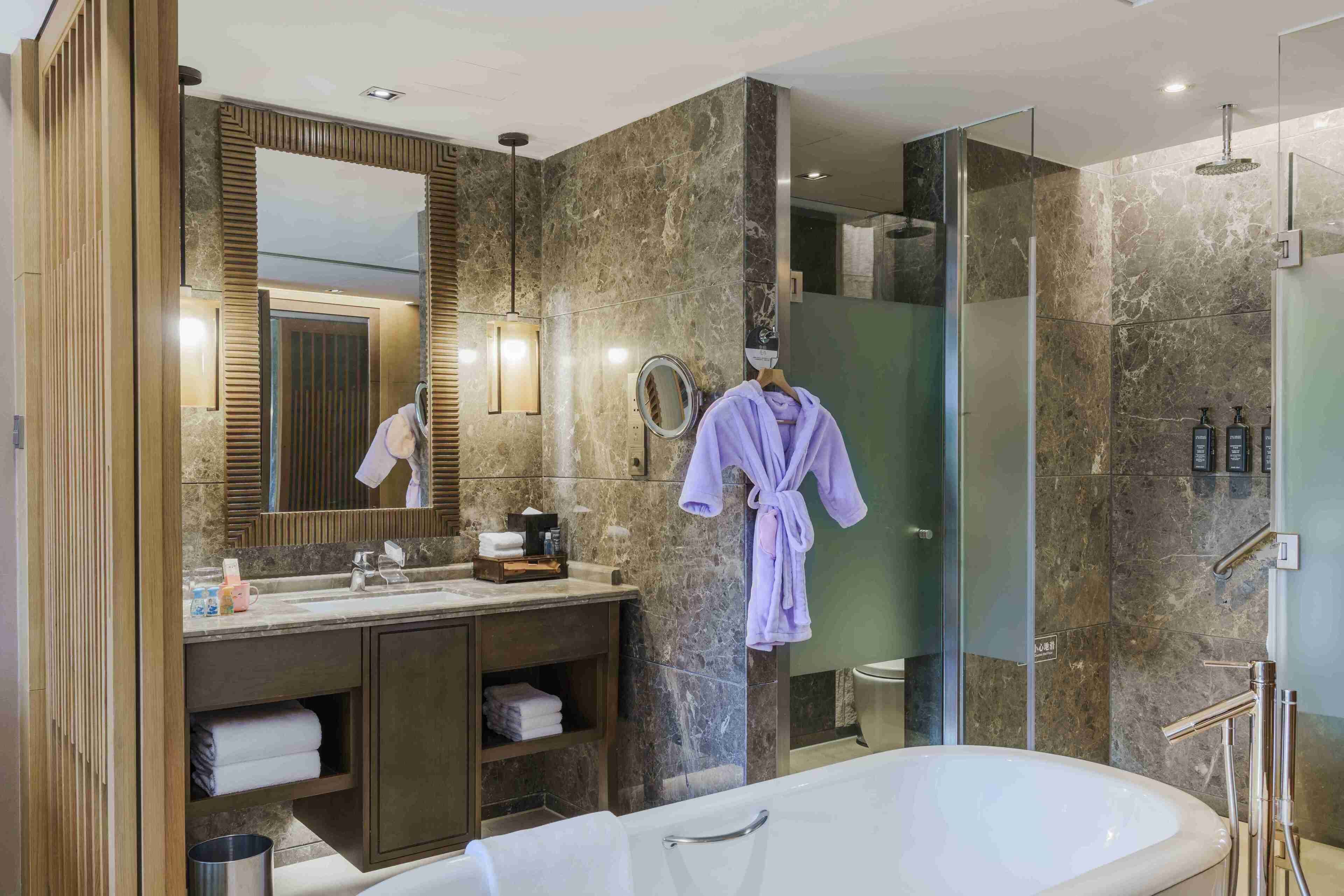 A modern bathroom with a large mirror, a bathtub, a shower area, and a vanity with a sink and towel rack.