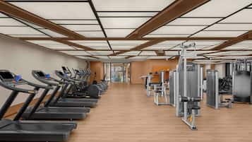 A gym with treadmills, weight machines, and a wooden floor.