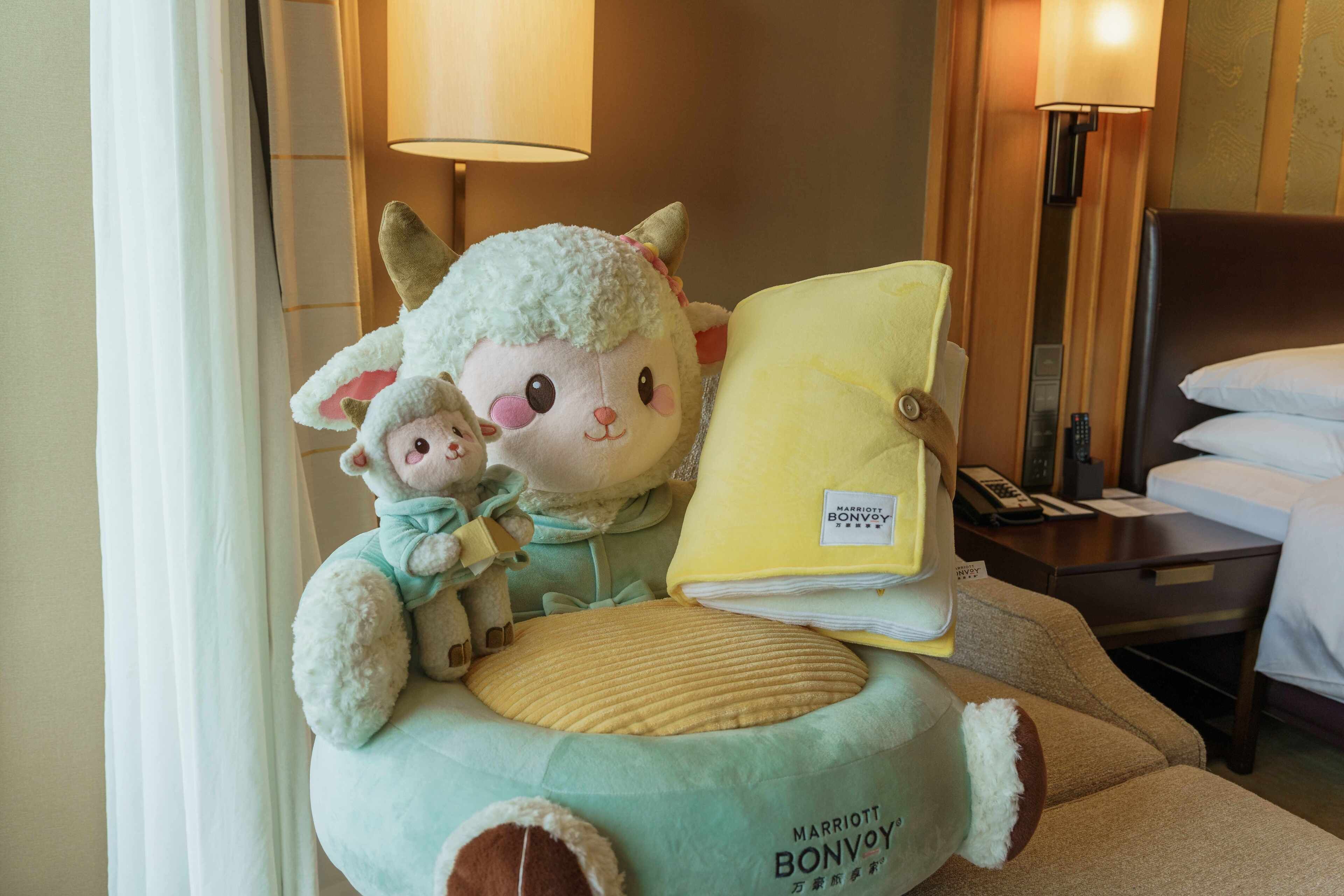 Un peluche con una almohada y una manta sobre una cama en una habitación de hotel.