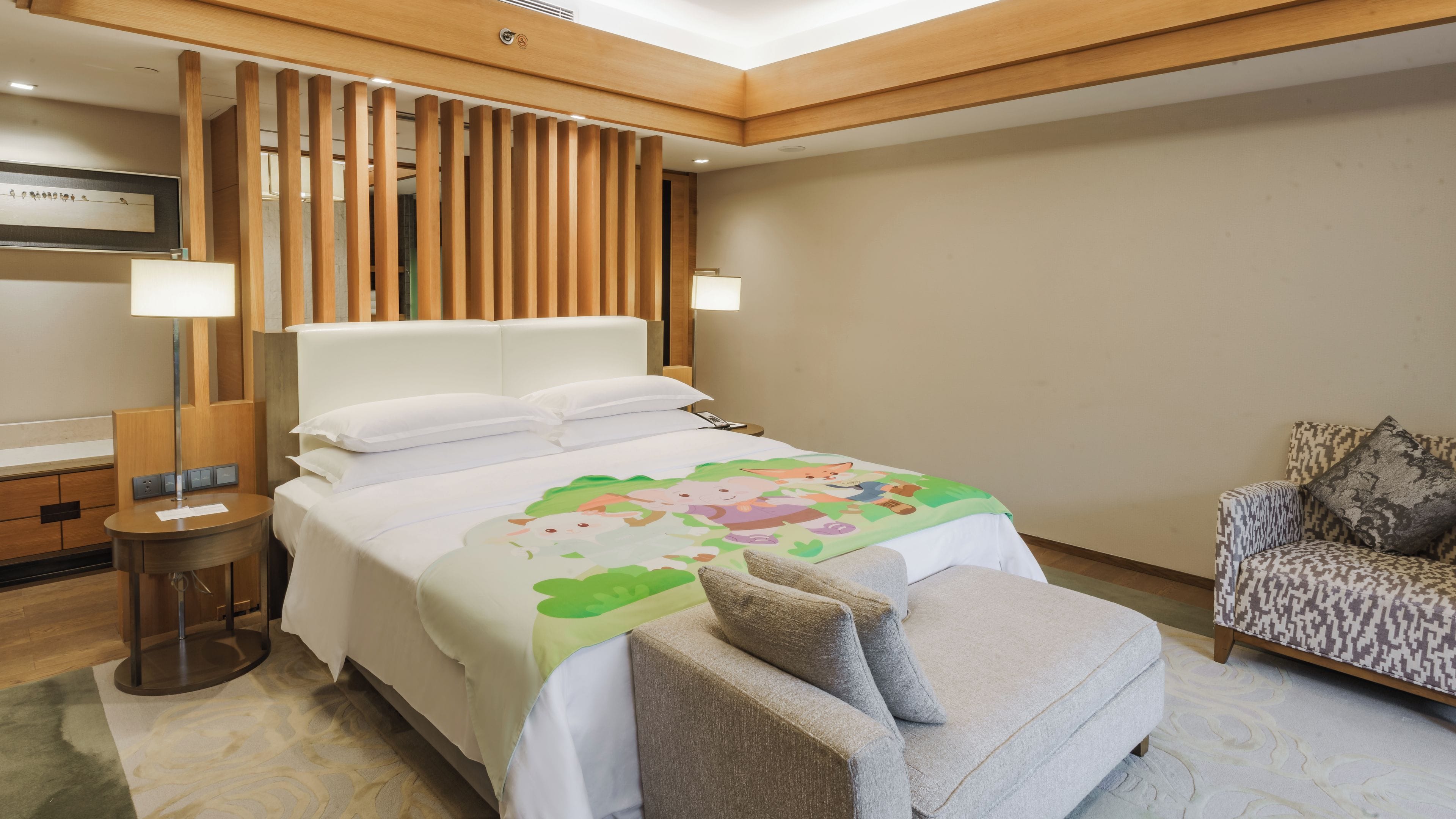 A hotel room with a bed, bedside lamps, a chair, and a small table.