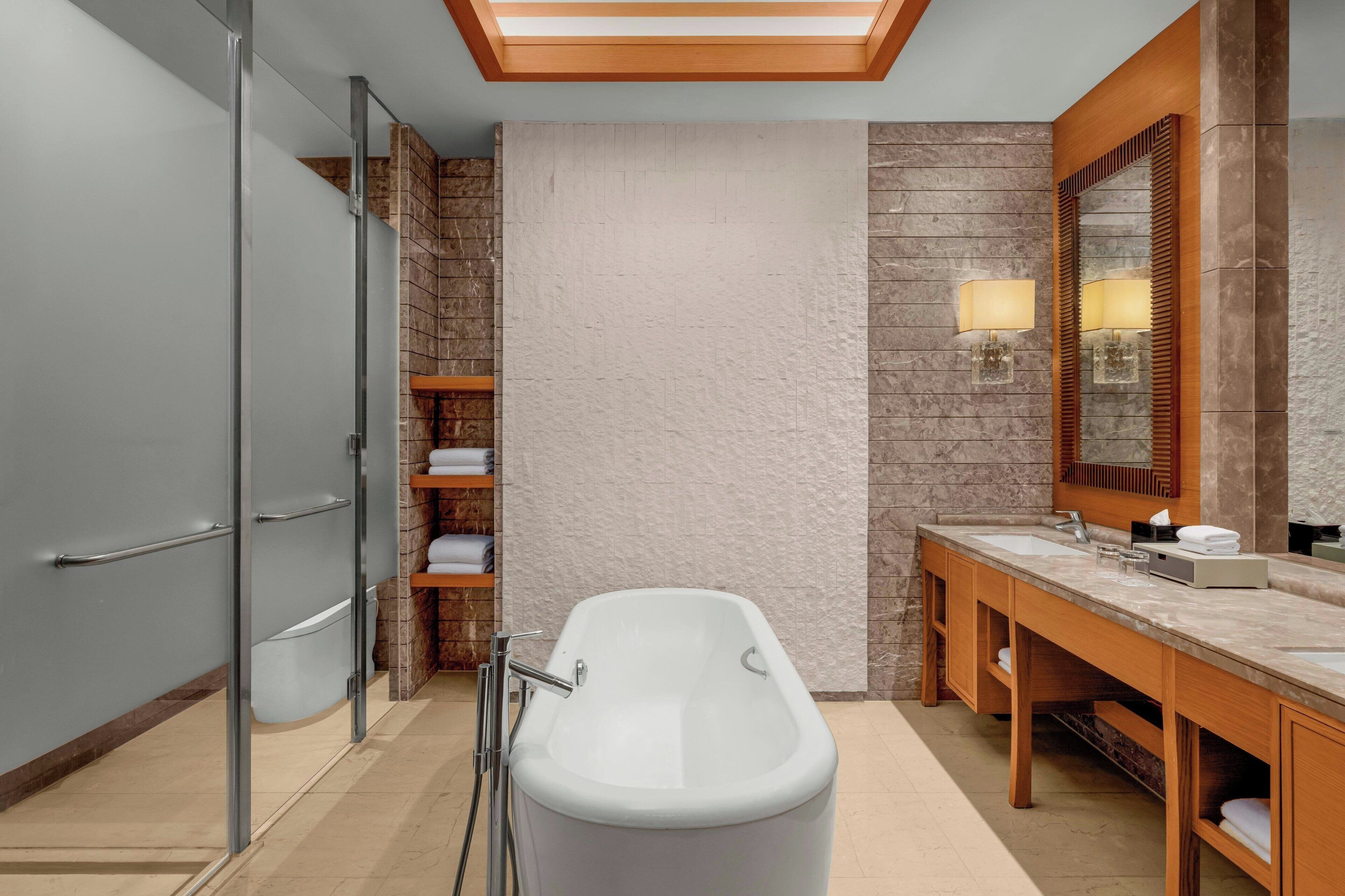A modern bathroom with a freestanding bathtub, a large mirror, and a wooden vanity.