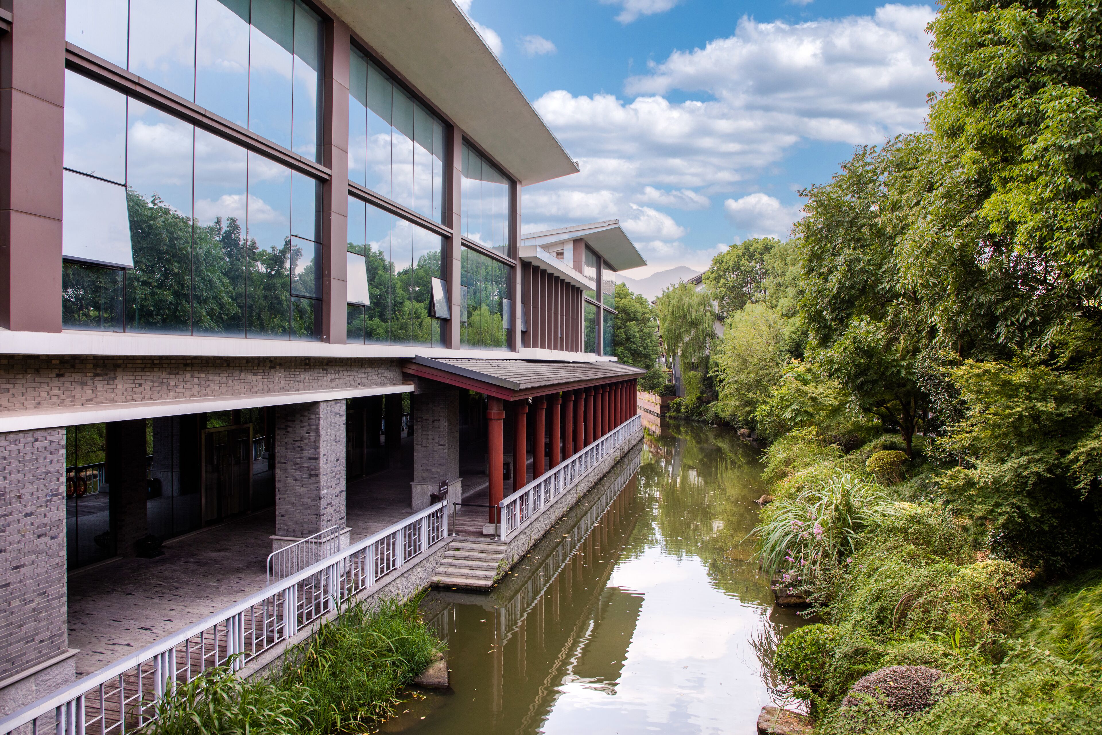 Un edificio moderno con grandes ventanales y un canal de agua al frente.