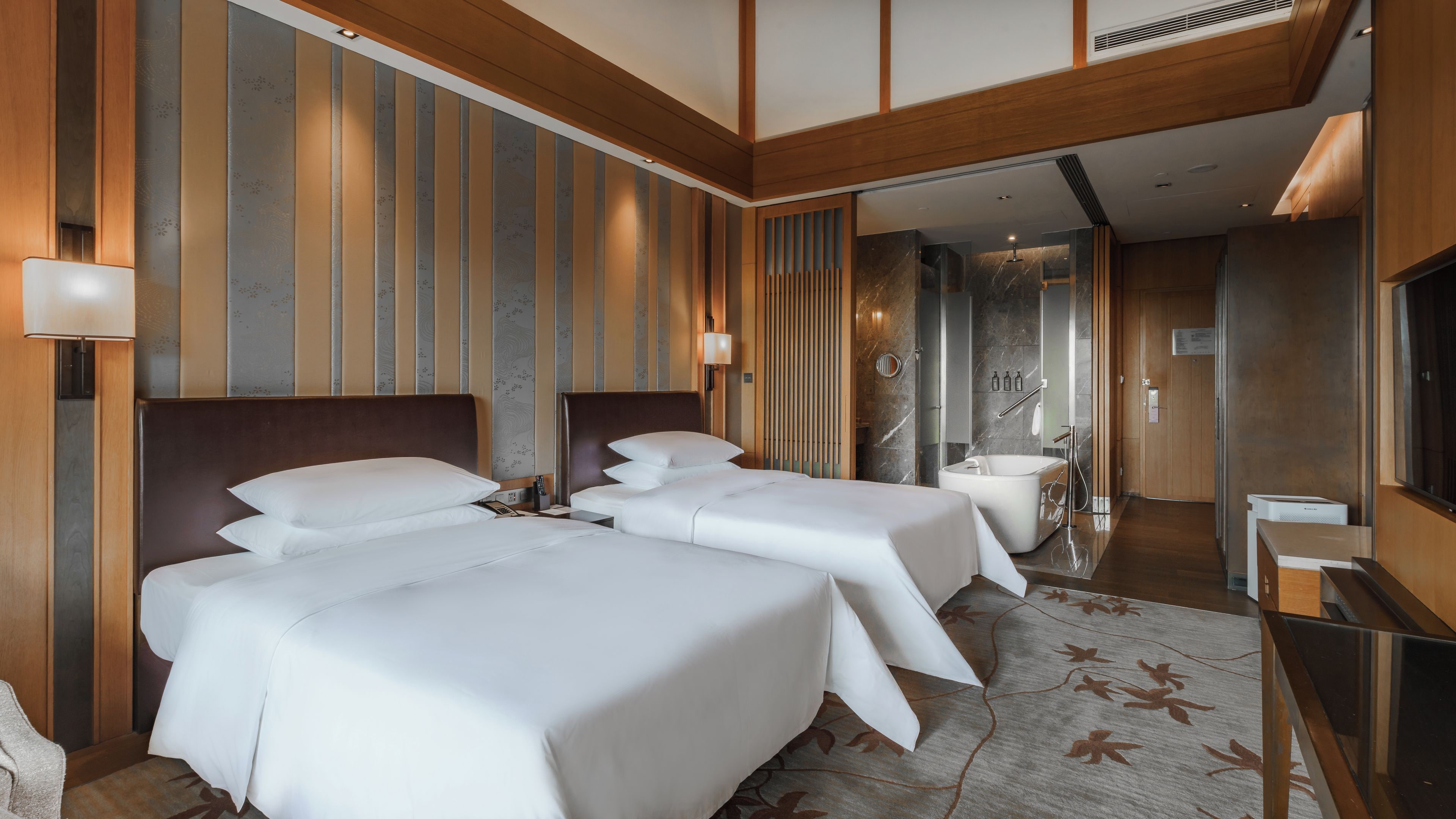 Ein Hotelzimmer mit zwei Betten, einer Duschkabine und einem Fernseher.