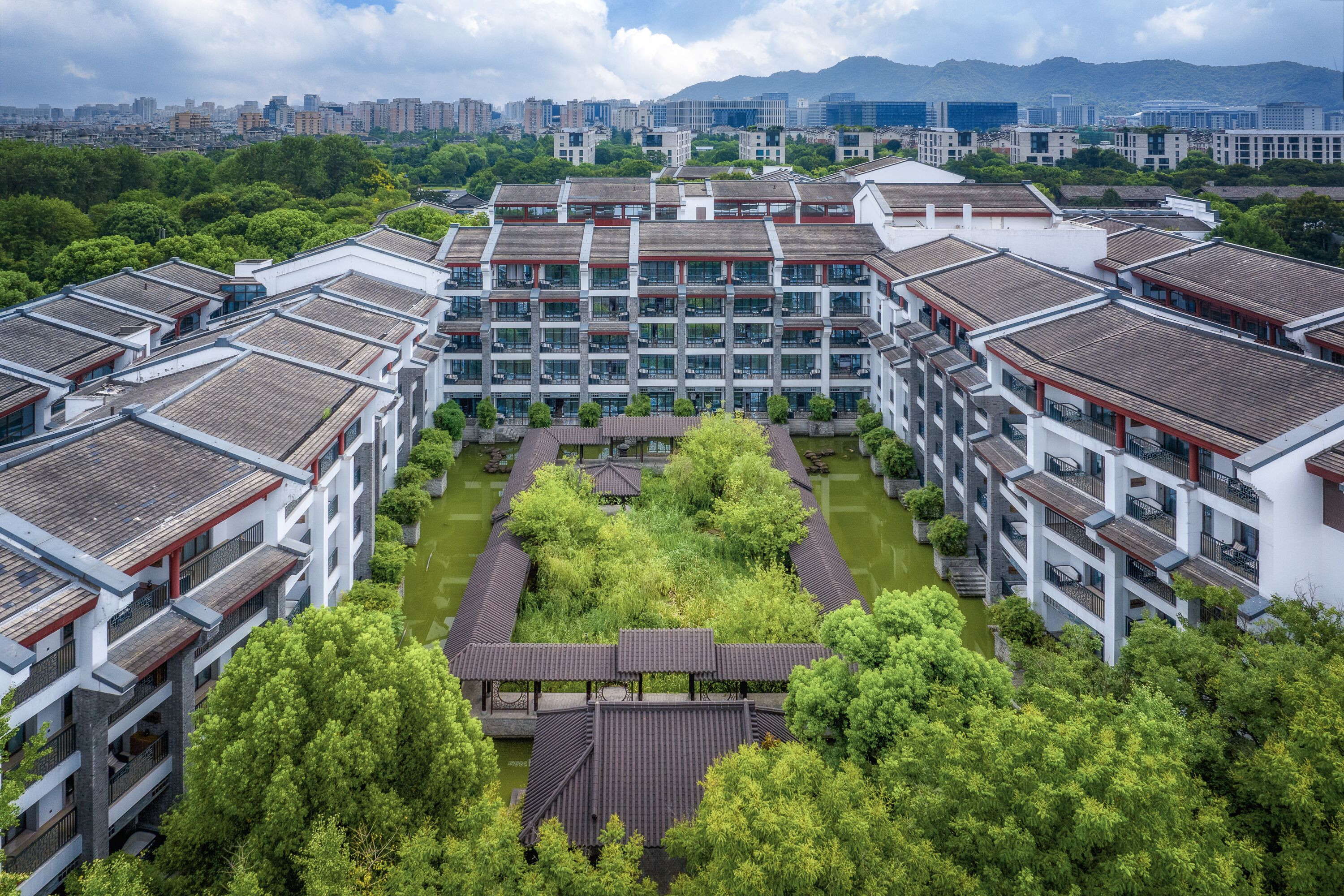 Un bâtiment moderne à étages, doté de grandes fenêtres et d’une cour intérieure arborée.