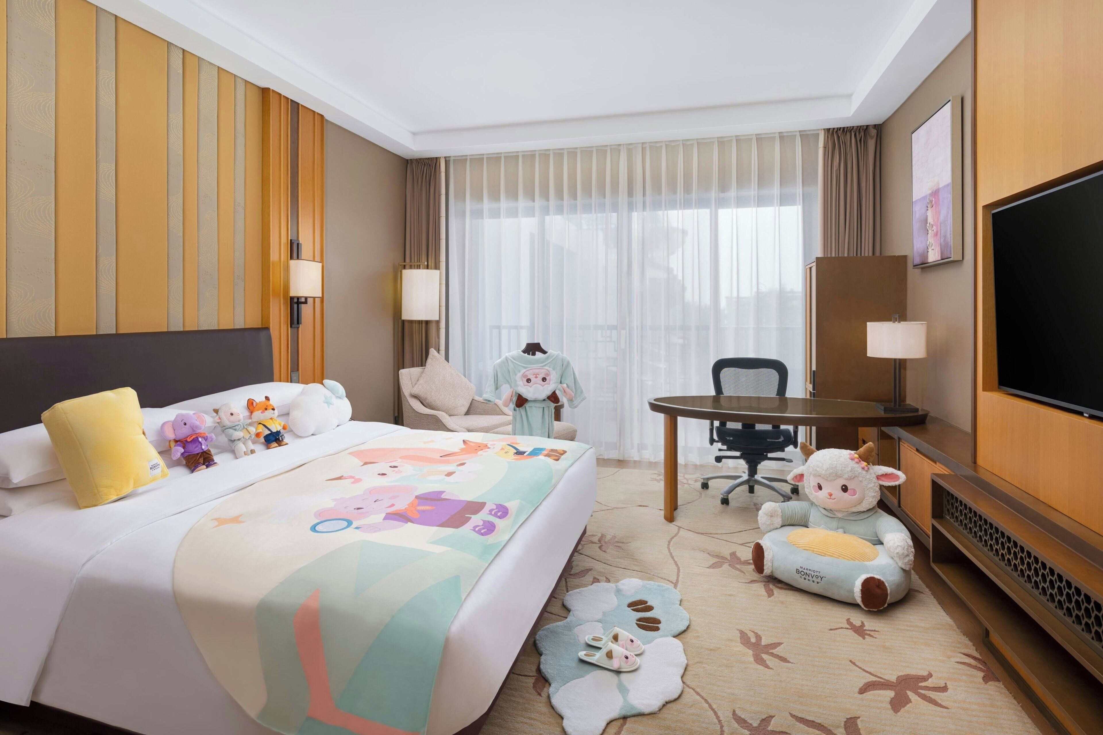 Une chambre d’hôtel avec un lit, un bureau, une télévision et une fenêtre avec des rideaux.