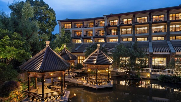 A hotel with multiple balconies, a courtyard with a pond, and traditional-style gazebos. - Sheraton Grand Hangzhou Wetland Park Resort (Hangzhou)
