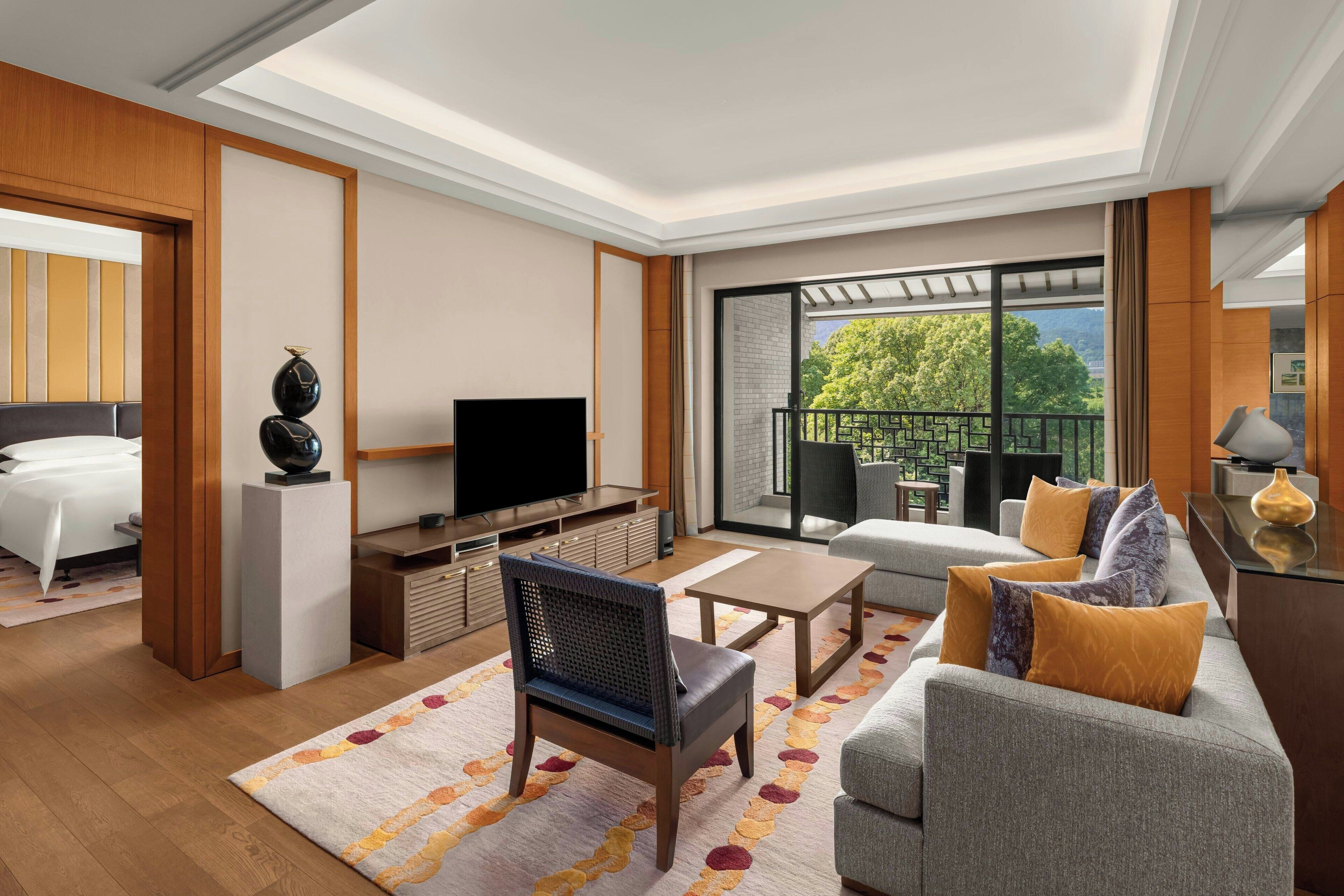 Une chambre d’hôtel moderne dotée d’un balcon, d’une télévision, d’un canapé et d’une table à manger.